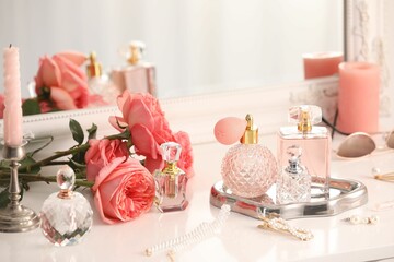 Bottles of different perfumes, accessories and flowers on dressing table indoors