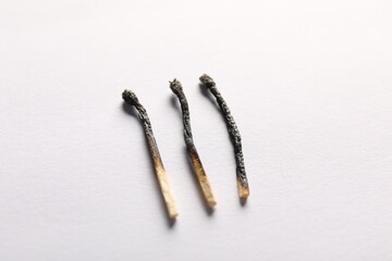 Burnt matches on light grey background, closeup view