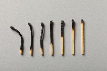 Burnt matches on grey background, flat lay