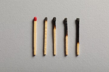 Burnt and whole matches on grey background, flat lay