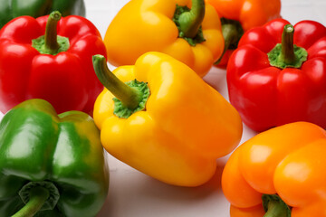 Fresh colorful bell peppers on light table, closeup