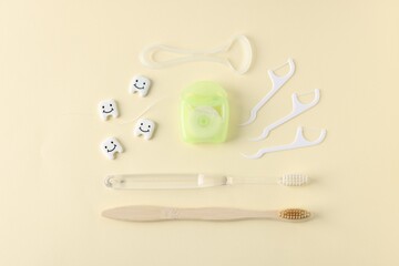 Different oral care products and teeth models on beige background, flat lay