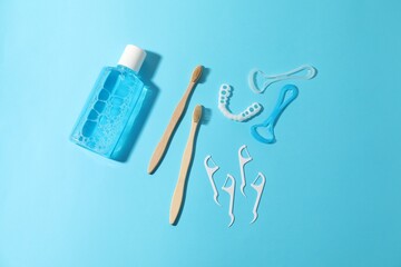 Different oral care products on light blue background, flat lay