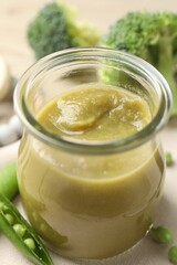 Baby food. Tasty puree in glass jar and ingredients on table, closeup