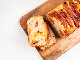 Peach cake loaf on wooden cutting board on white backgroud