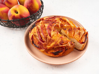 Vegan nectarine peach cake on white table, summer fruit pie
