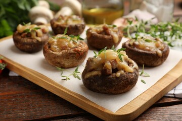 Delicious stuffed mushrooms with melted cheese and thyme on wooden table, closeup