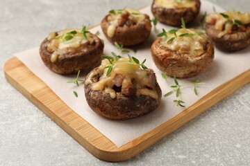 Delicious stuffed mushrooms with melted cheese and thyme on grey textured table, closeup
