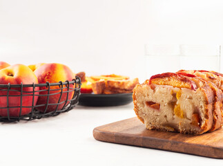 Peach cake loaf on wooden cutting board on white backgroud