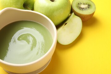 Baby food. Tasty puree in bowls and different ingredients on yellow background, above view. Space...