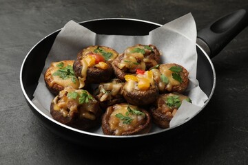 Tasty stuffed mushrooms in frying pan on black table, closeup