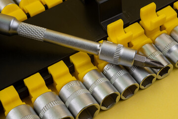 Precision tools arranged neatly with a screwdriver positioned among the socket set on a workbench