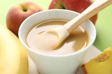 Baby food. Tasty puree in bowl and ingredients on green background, closeup