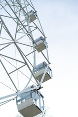 Ferris wheel cabins moving upward against a clear sky in an amusement park during daytime
