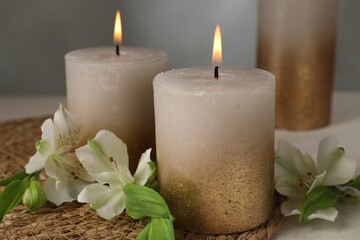 Burning candles and lily flowers on white table, closeup