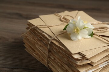 Stack of love letters and flowers on wooden table, closeup