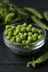 Fresh ripe green peas on black wooden table, closeup