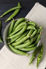 Fresh ripe green peas on black wooden table, flat lay
