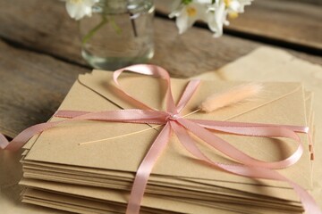 Stack of love letters and parchment sheet on wooden table, closeup