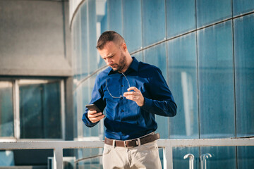 Man checking phone while standing outside a modern building