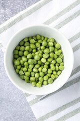 Fresh ripe green peas on grey table, top view