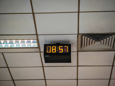 Old style electronic watch on the ceiling. Vintage digital clock. Industrial digital clock with luminescent digits