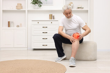 Senior man suffering from pain in knee at home