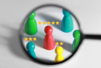 Employee search. Different colorful pawns with stars on white background, view through magnifying...