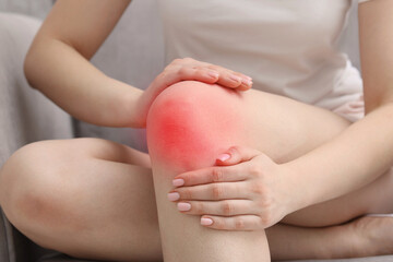 Woman suffering from pain in knee at home, closeup
