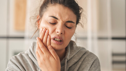 Young woman with toothache and holding her jaw
