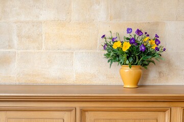 Colorful flower arrangement in yellow vase on wooden table against brick wall