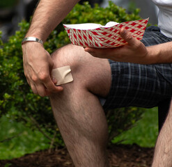 A hand taking off a Band-Aid on his knee 