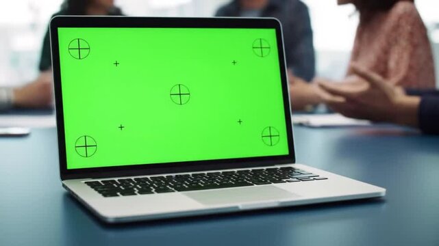  Laptop computer with a blank green screen on an office desk, perfect for chroma key compositing. A modern workspace mockup for business presentations, video calls, or custom content.