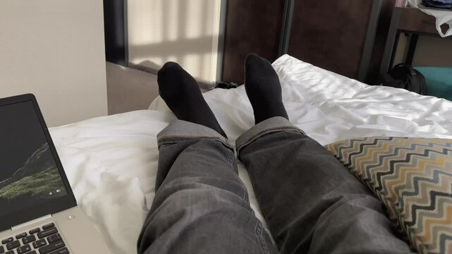 A freelancer enjoys the comfort of working from home, resting in bed with a laptop computer nearby