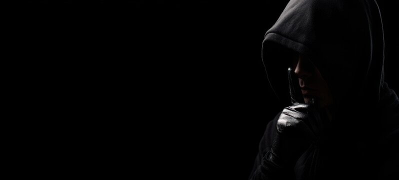 The hooded figure shrouded in mystery and intrigue against a dark backdrop.