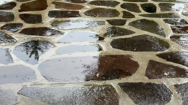 An abstract and peaceful background of rain creating patterns on a wet and reflective stone floor