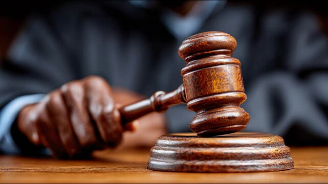 Judge's hand holding a gavel in a courtroom, representing legal decisions, justice system, law, and courtroom proceedings.
