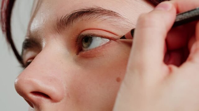 Eye shadow makeup to the upper eyeliner, close-up. Makeup artist applies a bright eye shadow with a makeup brush.Tutorial master class of professional makeup. 