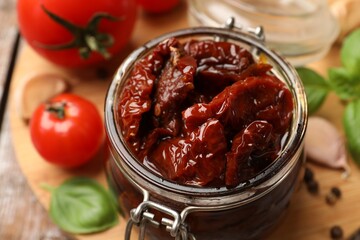 Tasty sun dried tomatoes, fresh vegetables and peppercorns on table, closeup