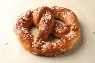 Tasty pretzels with salt on beige background, closeup