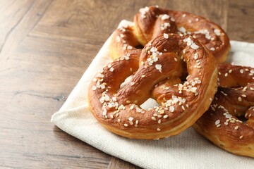 Tasty pretzels with salt on wooden table, closeup. Space for text