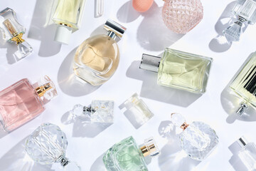 Luxury perfumes and beautiful lilac flowers on white background, flat lay
