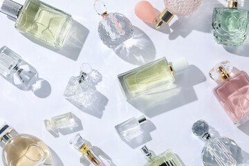Luxury perfumes and beautiful lilac flowers on white background, flat lay