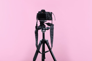 Modern professional video camera on pink background