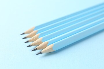 Graphite pencils on light blue background, closeup