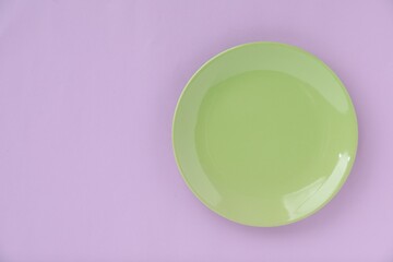 One empty plate on violet background, top view. Space for text