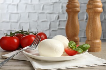 Tasty mozzarella cheese balls, tomatoes and basil on wooden table, closeup