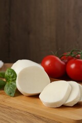 Tasty mozzarella, tomatoes and basil on wooden table, closeup