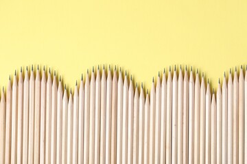 Many graphite pencils on yellow background, flat lay. Space for text
