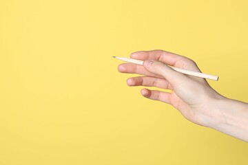 Woman with graphite pencil on yellow background, closeup. Space for text